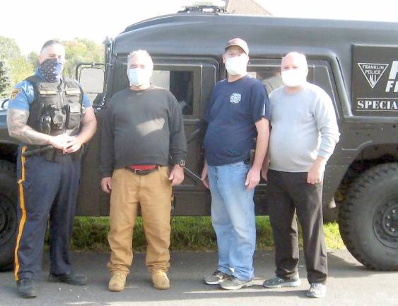 Franklin Officer Oren, church trustee Bob Winter, firefighter Stuart Cohen, and Pastor Stephen Vogt pose by the Franklin Special Unit Hummer (Photo by Janet Redyke)