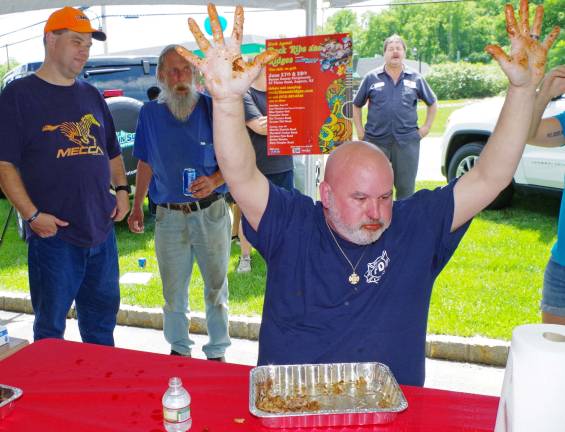Firefighter Jeff Walsh of Ringwood&#xfe;&#xc4;&#xf4;s Skyline Lakes Fire Department raises his barbecue-sauce-covered hands in victory after his winning time of two minutes and eight seconds.