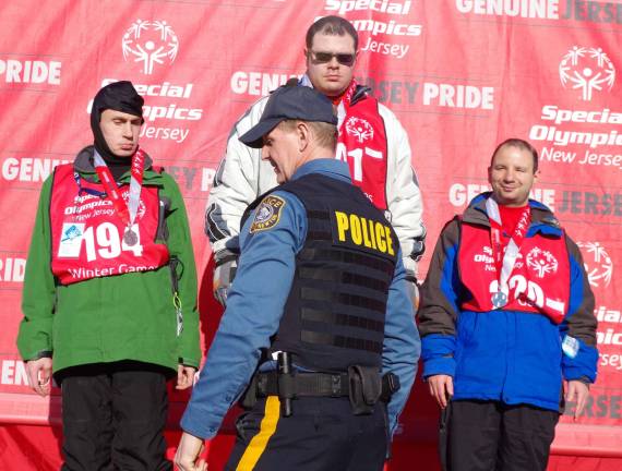 Retired Vernon Township Police Department Captain Stephen Moran, who now serves with the Newton Police Department, heads back to the sidelines after presenting another medal to a Special Olympics athlete.