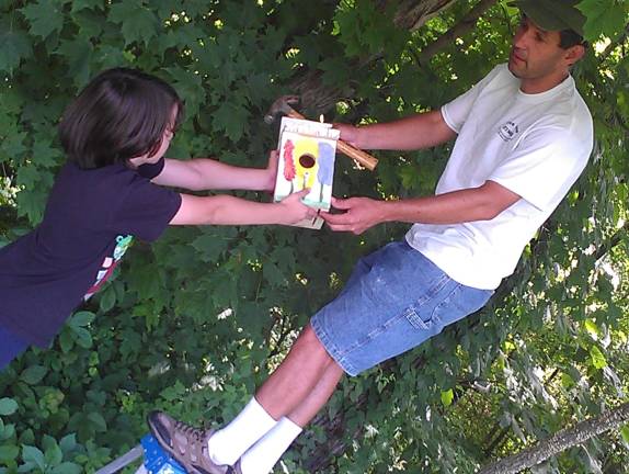 Club member Ethan Horn hands a finished birdhouse to Steve Wagner.