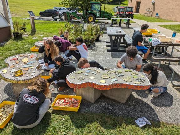 WV2 Pottery 1 students install mosaic tiles on the bench surfaces.