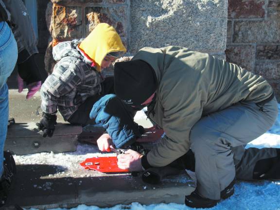 Photo by George Leroy Hunter A little boy gets help putting on snowshoes.