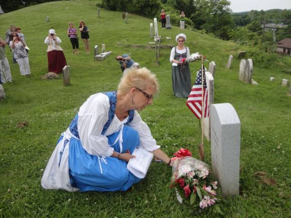 Event organizer Lisaann Permunian lays flowers at the newly dedicated gravestone of Revolutionary War veteran James Edsall, her fifth great-grandfather.