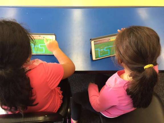 Second-grade students Keylee Ramirez and Mary Patti are shown helping the Fuzz Balls move through the maze in the app Kodable.