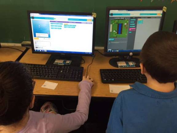Third-grade students Jessyca Schlereth and Noah DeRenzo are shown coding with both Elsa from Frozen and Steve from Minecraft.