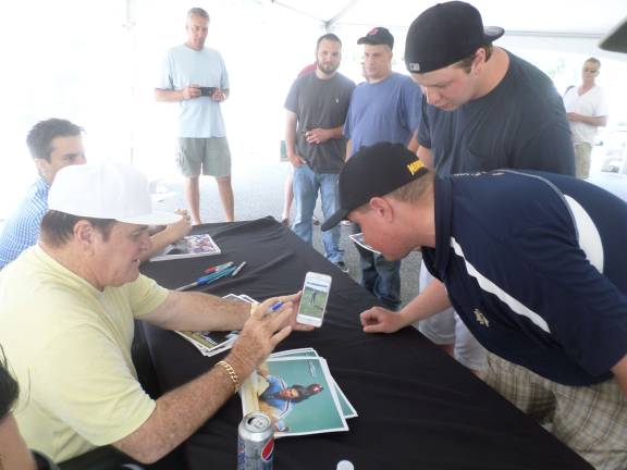 Billy McNeir, of Franklin, watches video of Pete Rose's grandson Pete Rose III, swinging a golf club, during an autograph signing at Franklin Sussex Automall on Saturday. McNeir coaches the Lenape Valley varsity golf team.