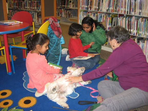 Ienduge and Enshuge Akabeeti along with their mom and Mazie&#xfe;&#xc4;&#xf4;s owner Catherine Bawa and Mazie enjoy a story about a mouse