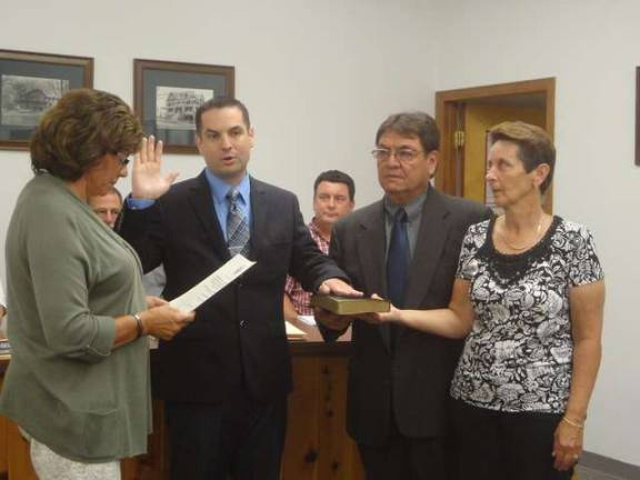 New Hamburg police officer Fred Moses is sworn in by Borough Clerk Doreen Schott during Monday's council meeting. His parents are at right.