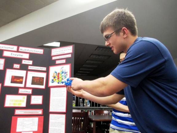Senior Aaron Wannemacher, 18 demonstrating the Peroxisomal Malfunction Enzyme with a model.