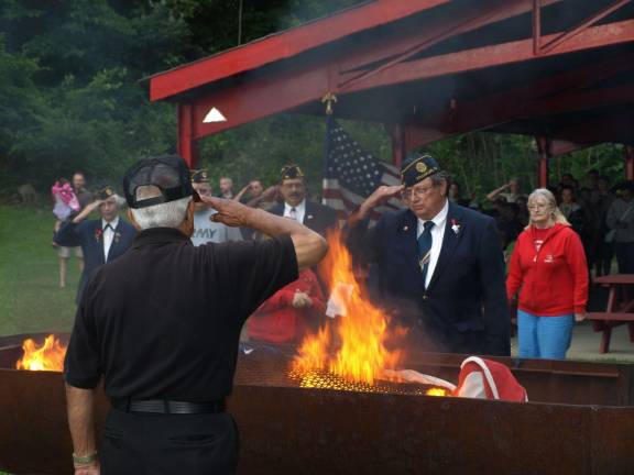 Legion members salute as the first flag burns.