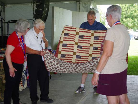 From left, &quot;Quilts of Valor&#xfe;&#xc4;&#xf9; presenter Barbara Thomas, quilt recipient retired Army Lt. Col. and Chaplain Ernie Kosa, Jeff Carr, and Gale Nederfield open Kosa&#xfe;&#xc4;&#xf4;s quilt for the audience to admire.