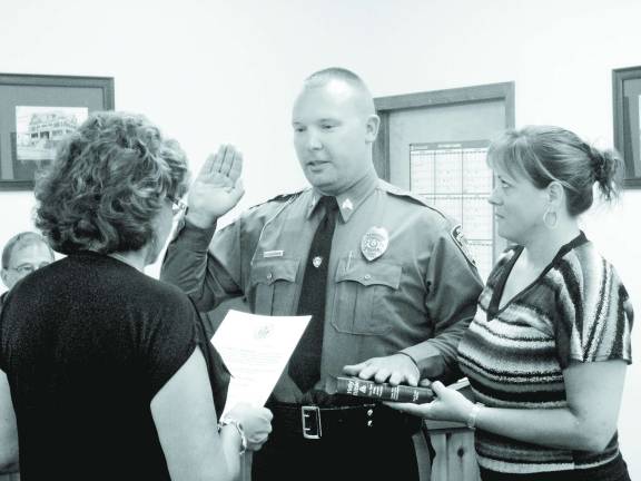 Photo by Scott Baker Borough Clerk Doreen Schott administers the oath of office to newly promoted Sgt. George Gunderman as fiancee Jacqui Machnik holds the Bible.