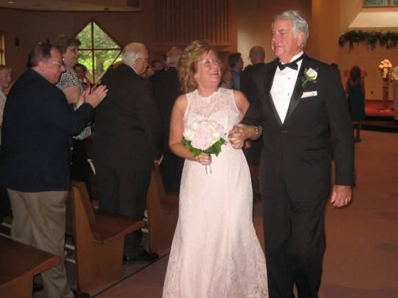 PHOTO BY JANET REDYKEThe newly married couple Kathy and Fred Barth walk together down the aisle of St. Francis de Sales Church after their ceremony.