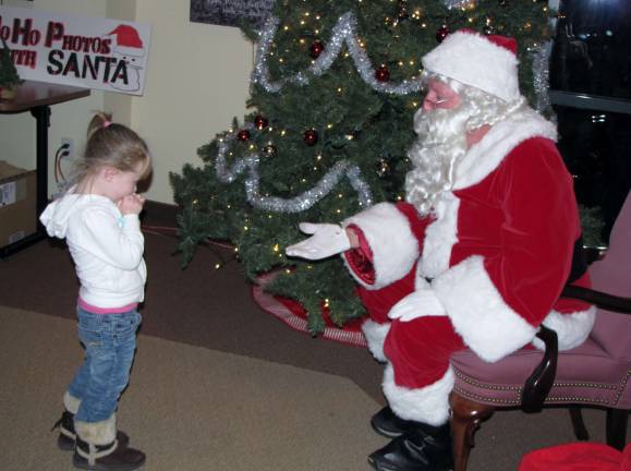 Three year old Hayleeana Quick reluctantly visits with Santa Claus at Project Self-Sufficiency&#x2019;s annual Holiday Party.