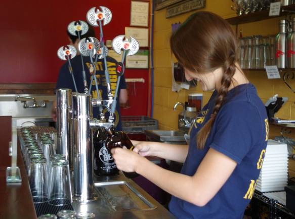 Angry Erik Brewing employee Ashley Schreyer fills another bottle at the tap during the fundraiser.