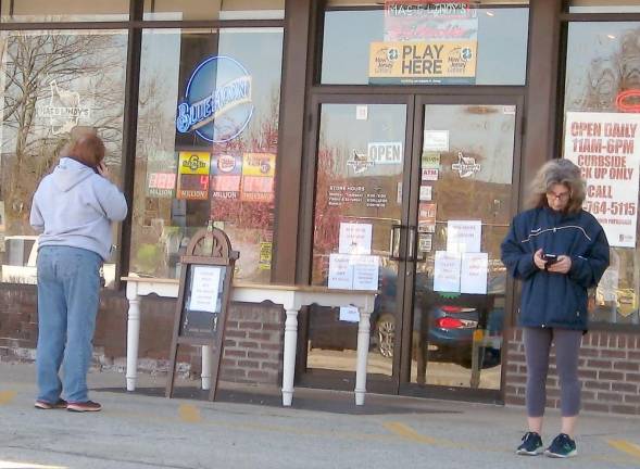 Customers distance themselves from one another as they wait outside Mac and Lindy's in the Acme Plaza in Vernon for their orders. Patrons are not allowed in stores for safety reasons.