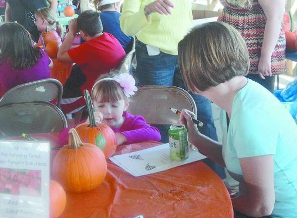 Sussex County celebrates fall with Harvest, Honey and Garlic Fest at Fairgrounds Madison Banuls, of Sparta, asks mom Catherine for help decorating her pumpkin.