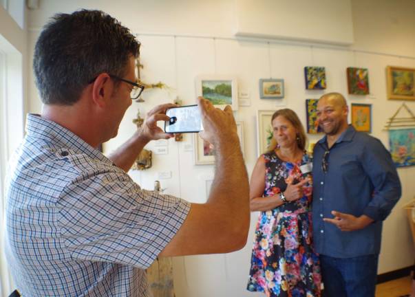 Painter and founder of the gallery, John Maione Jr. takes a photo of Phylis Barfoot and Qaasim Munoz during the opening reception. Munoz is from the Garden of Life Massage &amp; Yoga Center, which also is located at the Town Center at Wantage.
