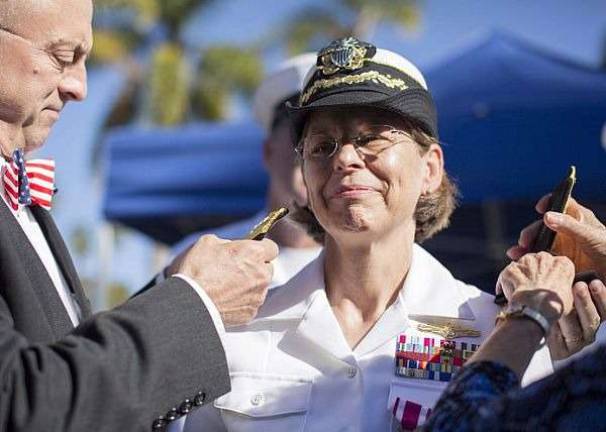 Rear Adm. Linnea J. Sommer-Weddington receives her rear admiral shoulder boards from her husband, Andy Weddington, at her promotion ceremony.