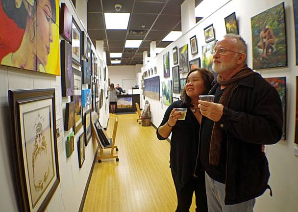 Amy Parrell of Franklin and Rick Boydston of Vernon are shown appreciating portraits created by Vernon artist Qaasim Munoz.