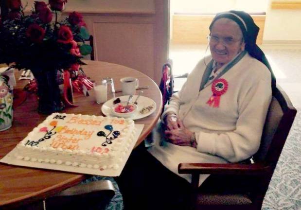 Sr. Mary Urban Harrer is shown with a cake marking her 102nd birthday.