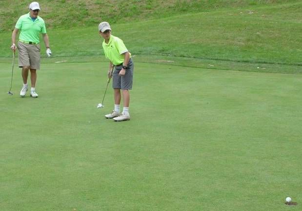 Avery Cohen sinks a 19 foot put to secure the win for his team as father Gordon looks on.
