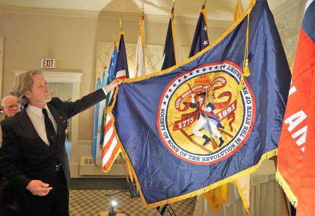 Former President Gerald G. DeGroat of the Society of the Sons of the Revolution shows their New Jersey flag.
