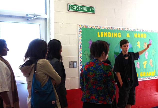 At the far right, tour guide and 8th grade student Krystian Kipp, 14, led the visitors through the Hamburg School hallways and taught them about the unique and yet often-recurring themes found in each corridor. Here Kipp teaches them about the Six Pillars of Character: trustworthiness, respect, responsibility, fairness, caring, and citizenship.