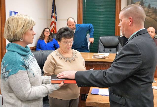 PHOTOS BY VERA OLINSKI On right, Councilman Robert Gunderman repeats oath of office. From left, Cynthia Gunderman holds the Bible, and Borough Clerk Phyllis Drouin administers oath.