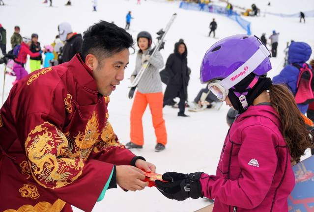 Jordan, on left, gives a Chinese red envelope with raffle ticket to a young guest.