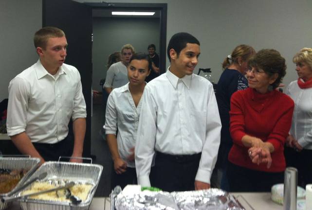 Teens and volunteers serve dinner for veterans.