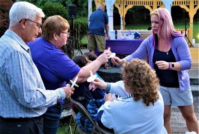 Vigil organizer Angela Lamendola helps light the candles of those in attendance at a candlelight vigil for Christine Solaro, 37, who was allegedly fatally shot by estranged husband Acting Newark Police Lt. John Formisano July 14.