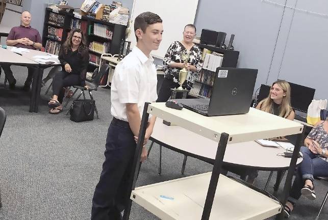 Nicolas Marchionda at the school board meeting, his teacher Valerie Reeth pictured behind him