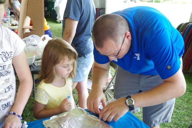 At right, Corey Brown, Associate Executive Director of the Sussex County YMCA offered the children the chance to make foil boats to float pennies in a tub of water.