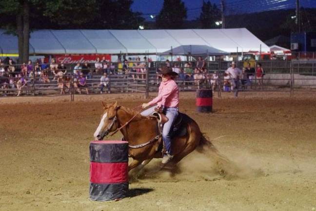 Bucking broncos at the NJ State Fair Rodeo cowgirl JoyLynn Leech of Wantage, New Jersey and her horse moving fast during the barrel racing contest. The Green Valley Farms Rodeo took place at the Sussex County Fairgrounds on Saturday, August 1st 2015. Cowboys and cowgirls from across the United States and South America participated in the two day event. Green Valley Farms is located in Wantage, New Jersey. The fairgrounds are located in Augusta, New Jersey.