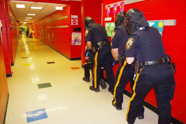 Photo by Chris Wyman Four Vernon police officers are shown during a drill about to enter a classroom in search of three gunmen.