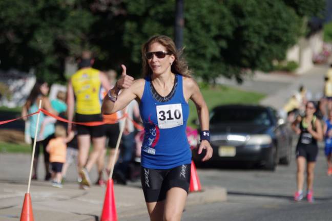 Forty-seven-year-old Triathlete Cheryll Martino, of Sparta, gives the thumbs up signal as she runs in the triathlon. photos by george leroy hunter