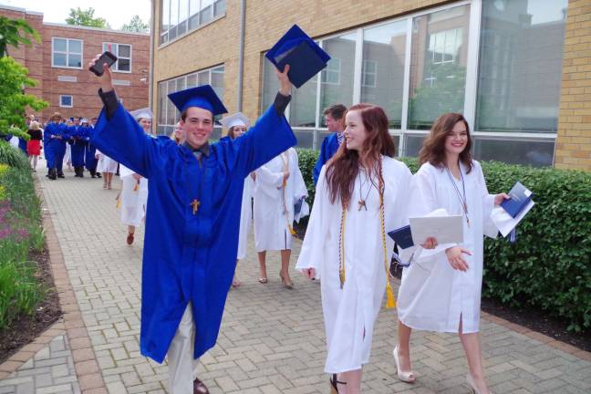 Pope John graduate Tyler Prime raises his arms in excitement after receiving his diploma.