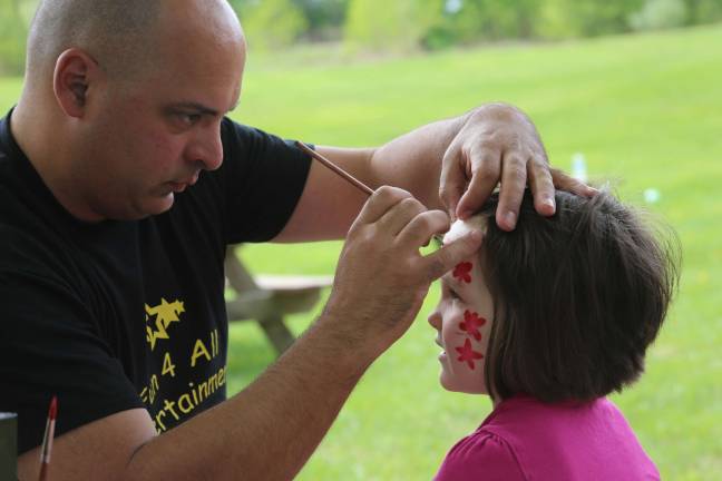 Maddie Weis of Branchville gets a flower garden painted by Mike Iradi in Franklin at the Owiepalooza fundraiser.