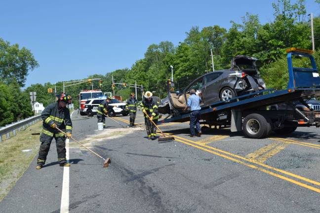 Sparta Township Fire Chief Craig Wilson and several other Sparta Firefighters help clear the highway following Monday's six-vehicle crash.