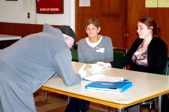 Poll workers Lorraine Franek of Hamburg (left) and Alexis Redner of Wantage watch as a Franklin resident signs in to cast his ballot at the town&#xfe;&#xc4;&#xf4;s American Legion Post. The poll workers agreed that the turnout for this election was very good.