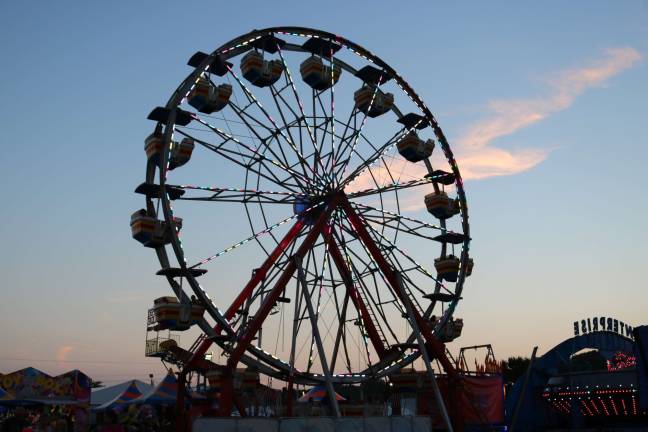 Fairgoers enjoy the Ferris Wheel during twilight.