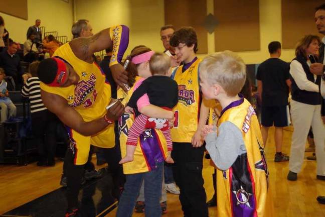 Harlem Wizards dazzle locals on the court Harlem Wizard Leon "Space Jam" Sewell autographs a young fans jersey.