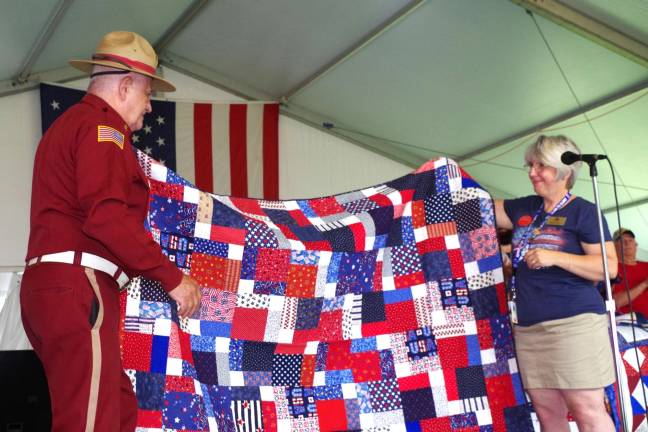 Wallkill Valley VFW Memorial Post 8441 of the Veterans of Foreign Wars Commander Jim Davis is shown accepting a Quilt of Valor for Vernon resident and veteran Bob Wallace. At the right is presenter Barbara Thomas of Wantage, the fair's director of creative home and hobby efforts.