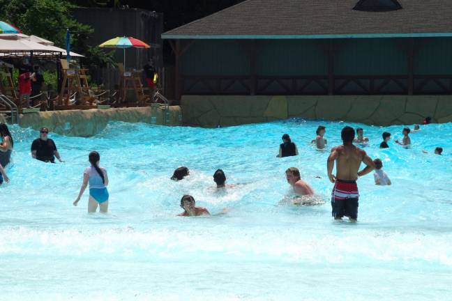 Visitors are shown enjoying the up and down motion of the Hightide Wavepool at Mountain Creek Water Park.