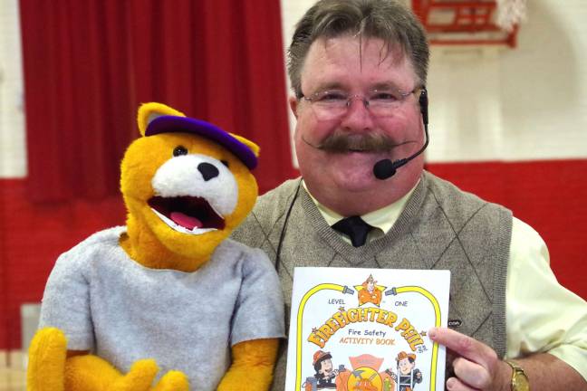 Firefighter Phil, portrayed by ventriloquist Dave Carr with the help of &#xfe;&#xc4;&#xfa;Al E. Cat&#xfe;&#xc4;&#xf9; holds one of three activity books that were given to the students at the Hamburg School.