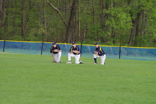 A trio of Jefferson Falcons take a knee in the outfield during a break.