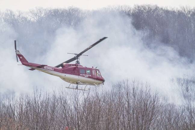 A state forest fire helicopter flies over the fire scene in Vernon at noon on Tuesday.