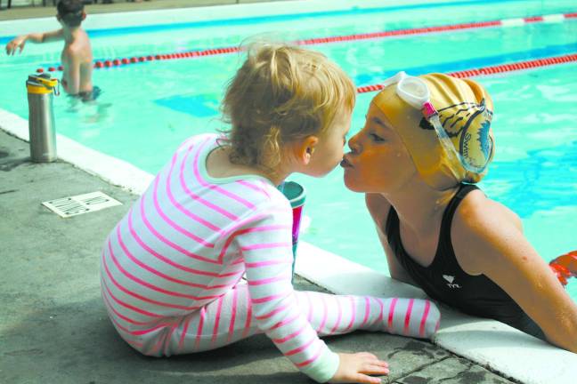 Volunteer group hosts swim-a-thon Swimmer Ella Duphiney takes a break in between laps to kiss her sister, Tessa.