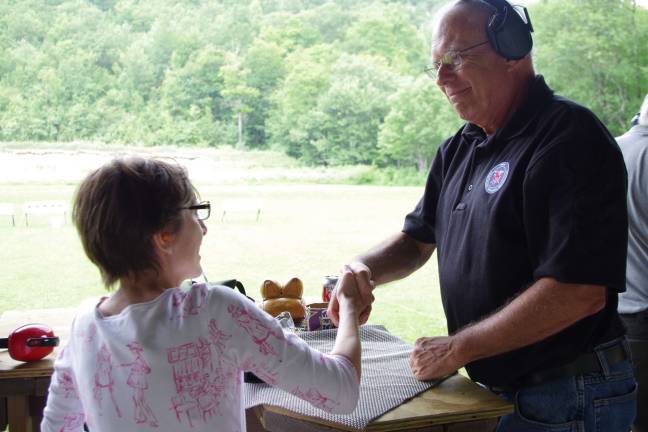 Rifle instructor Rich Choate of Byram congratulates Anita Collins of Hamburg for her first attempt at the falling plates range. It was Collins' first time shooting firearms.